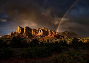 Скалы на возвышенности и радуга